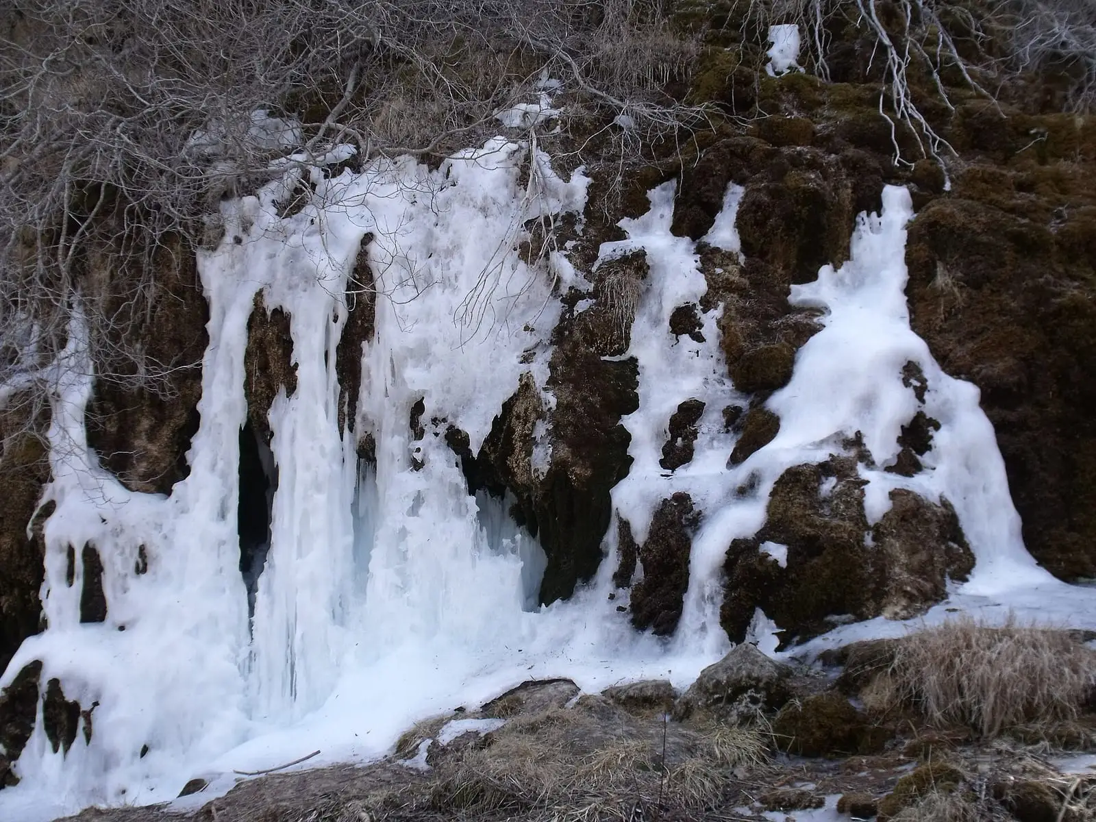 Cascada helada sobre rocas y musgo en el nacimiento del Cuervo